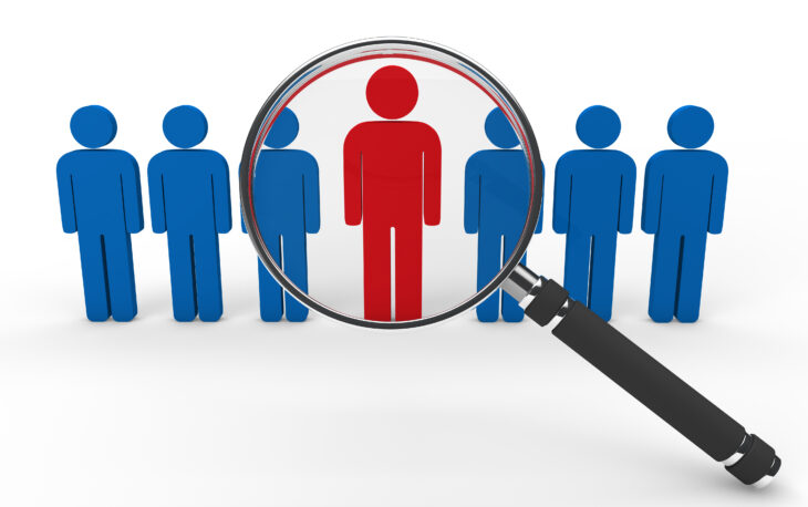 Magnifying glass highlighting a standout candidate among multiple people icons – concept of recruitment and talent selection